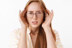 concerned clueless perplexed good looking stylish woman glasses frowning squinting holding hands temples head being troubled suffering headache white wall